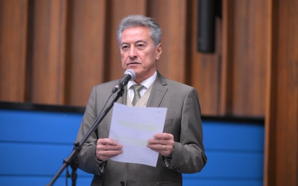 Roberto Hashioka discursa ao microfone na tribuna da Assembleia Legislativa de Mato Grosso do Sul, segurando um documento.
