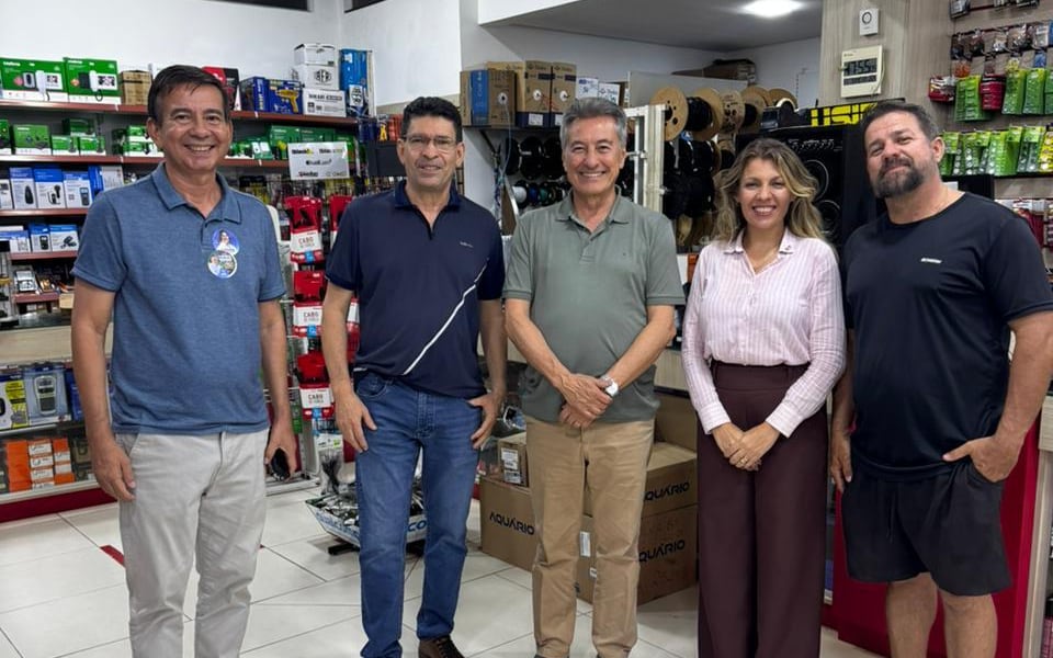 Roberto Hashioka ao lado de quatro pessoas no salão de uma loja de eletrônicos, entre prateleiras de componentes e caixas de produtos.