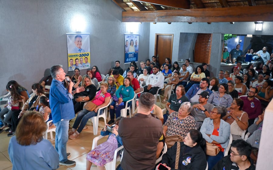 Roberto Hashioka fala ao microfone diante de dezenas de moradores reunidos em uma casa de eventos no Jardim Canguru, em Campo Grande.
