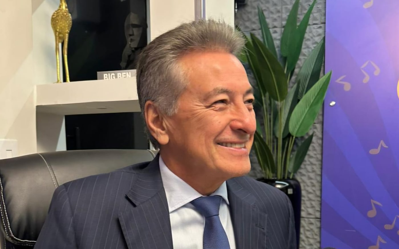 Roberto Hashioka sorri durante conversa, sentado em seu gabinete.